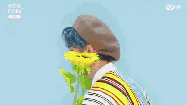 a boy with blue hair is holding a bunch of yellow flowers