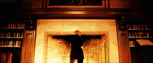a man is standing in front of a fireplace with the words kimlennon written on the bottom right