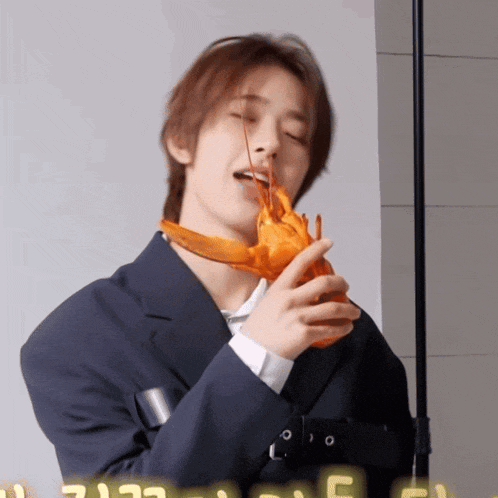 a man in a suit is holding a lobster in his hands