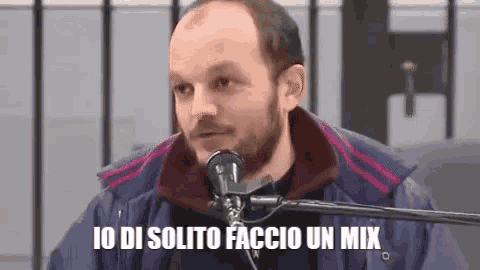 a bald man with a beard is sitting in front of a microphone and says io di solito faccio un mix