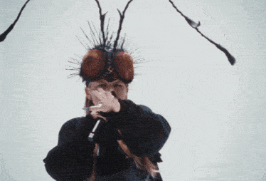 a woman is wearing a fly headpiece and holding a microphone