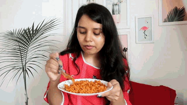 a woman is eating noodles with a fork from a white plate