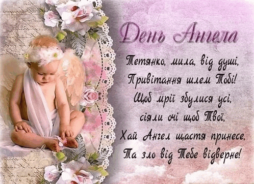 a baby with angel wings is sitting on a bed with flowers and a greeting card in a foreign language .