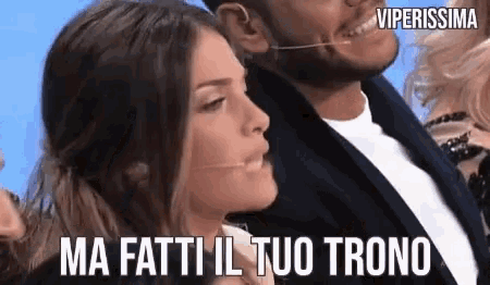 a man and a woman are sitting next to each other and the woman is saying ma fatti il tuo trono .