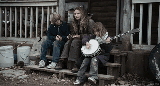 a girl playing a banjo sits on the porch of a house