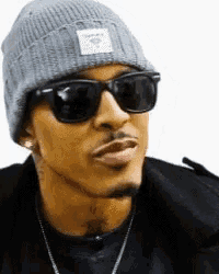 a man wearing sunglasses and a beanie is looking at the camera