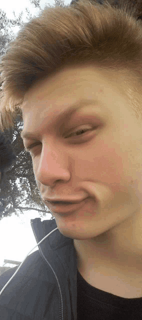 a close up of a young man making a funny face with his eyes closed