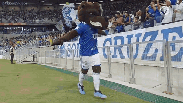 a mascot in a blue shirt stands on a soccer field