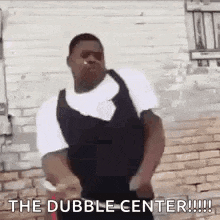 a man is dancing in front of a brick wall with the words `` the dubble center '' .