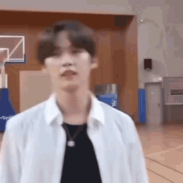 a young man in a white shirt and black shirt is standing in a gym .