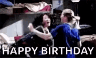 two women are hugging each other in a room with the words `` happy birthday '' written in the corner .