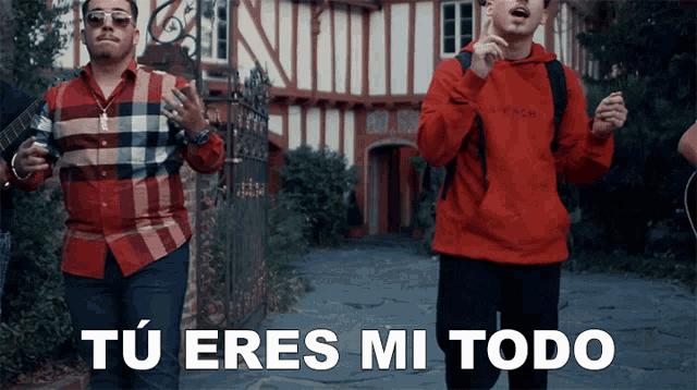 a man in a red hoodie says " tu eres mi todo " in front of a man in a plaid shirt