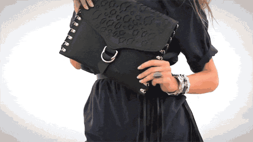 a woman in a black dress is holding a black clutch
