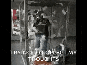a man is standing in a glass box with a bunch of money falling out of it .