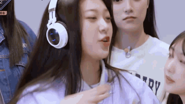 a girl wearing headphones and a purple shirt is standing next to two other girls .