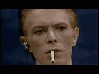 david bowie is smoking a cigarette in a close up of his face .