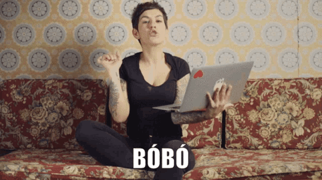 a woman is sitting on a couch with a laptop and the word bobo is on the couch