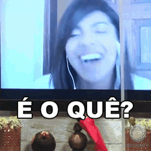 a woman is smiling in front of a tv with the words " e o que " written above her