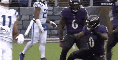 a football player in a purple jersey is kneeling on the field .