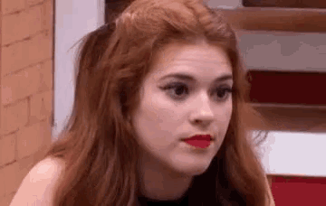 a close up of a woman with red hair and red lips making a funny face .