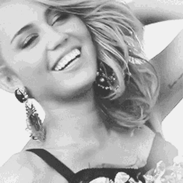 a black and white photo of a woman wearing earrings smiling