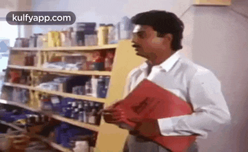 a man is holding a red folder in front of a store shelf .
