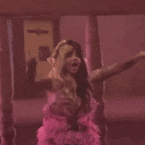 a woman in a pink dress is dancing with her arms outstretched in a room .