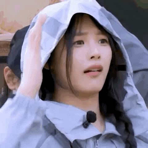 a close up of a woman wearing a hooded jacket making a funny face .
