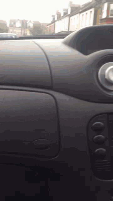 a close up of the dashboard of a car with a row of houses in the background