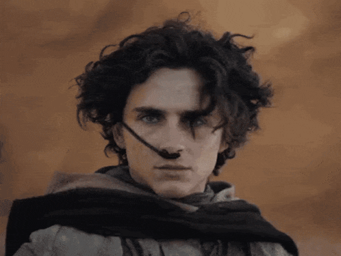a man with curly hair is wearing a scarf around his neck and a headset on his nose .