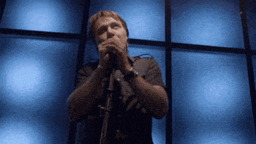 a man singing into a microphone in front of a blue background