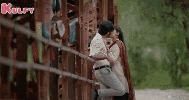 a man is holding a woman in his arms and kissing her on the cheek .