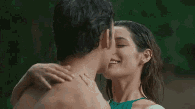 a man and a woman are kissing in a forest .