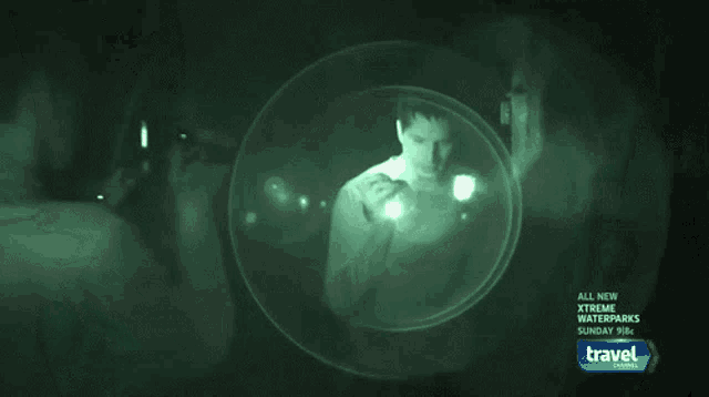 a man in a white shirt is standing in a dark room with a travel channel ad behind him