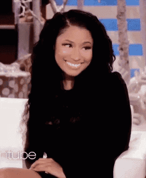a woman with long black hair is smiling while sitting in a chair with the word ellentube on the bottom right corner .