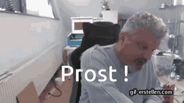 a man is sitting in a chair with the word prost written on the screen
