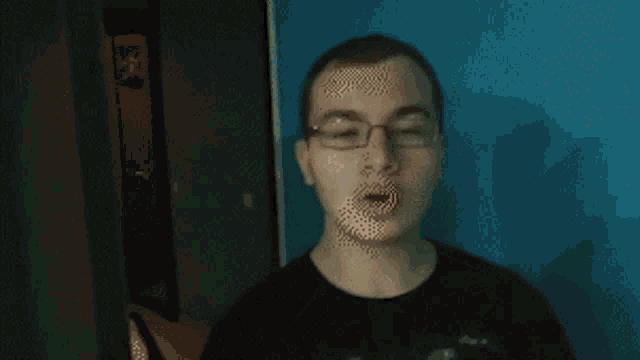 a young man wearing glasses and a black shirt looks at the camera