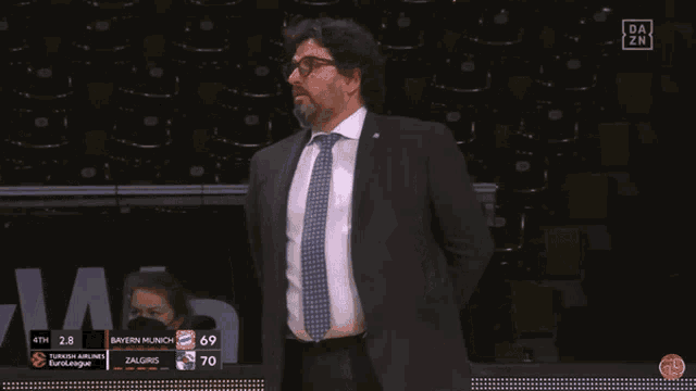a man in a suit and tie stands in front of a scoreboard that says bayern munchen