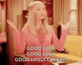 a woman in a pink sweater is sitting on a couch with her arms outstretched and saying good luck .