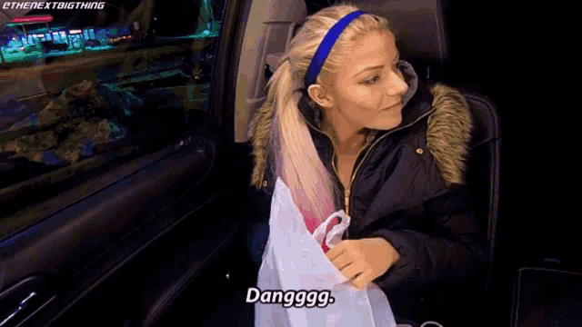 a woman in a car is holding a bag and says " danggg "
