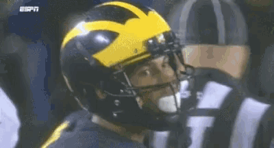 a close up of a football player wearing a yellow helmet