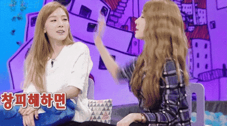 two women are sitting next to each other and one of them is giving the other a high five in korean