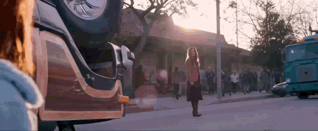 a woman is standing on the side of the road next to a car that has fallen off the road .