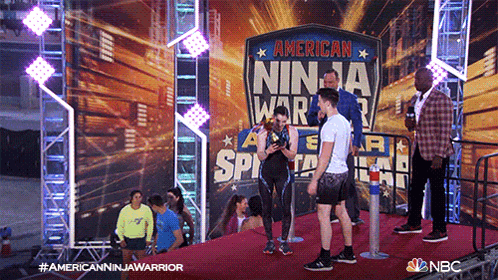 a group of people standing on a red carpet in front of a sign that says american ninja warrior