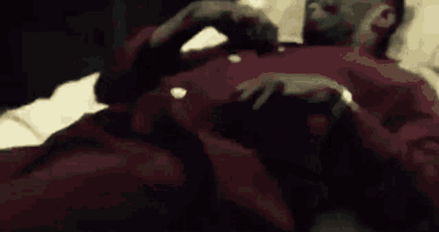 a man in a red shirt is laying in bed .