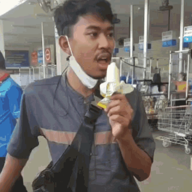 a man wearing a mask is holding a banana in a store .