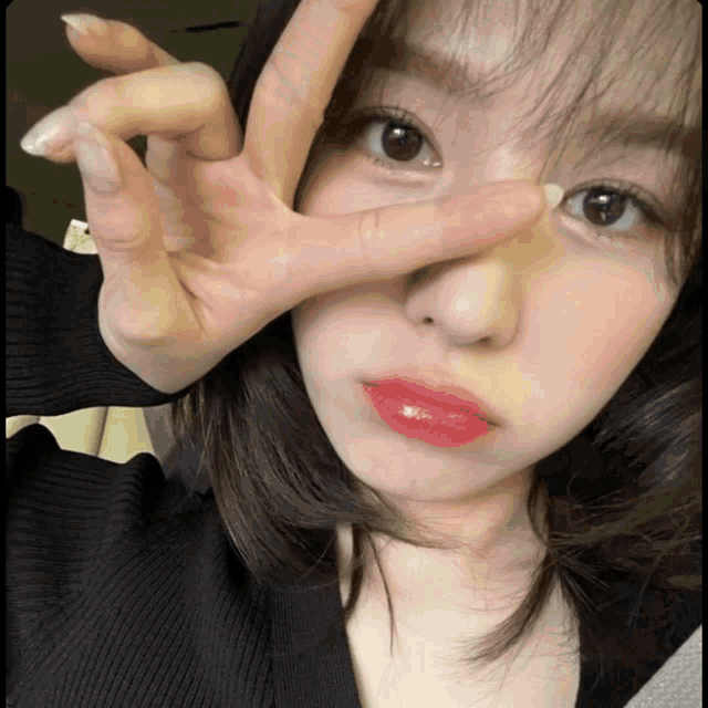 a woman making a peace sign with her hand over her face