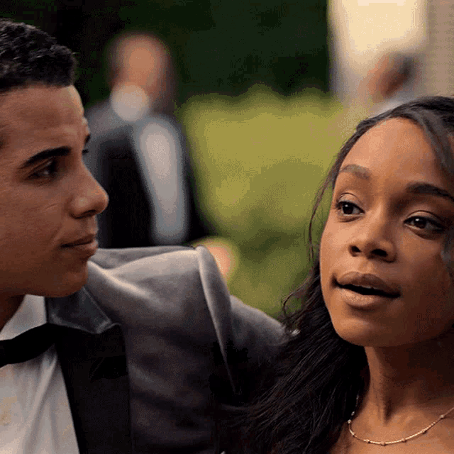 a man in a tuxedo and a woman in a dress are looking at each other