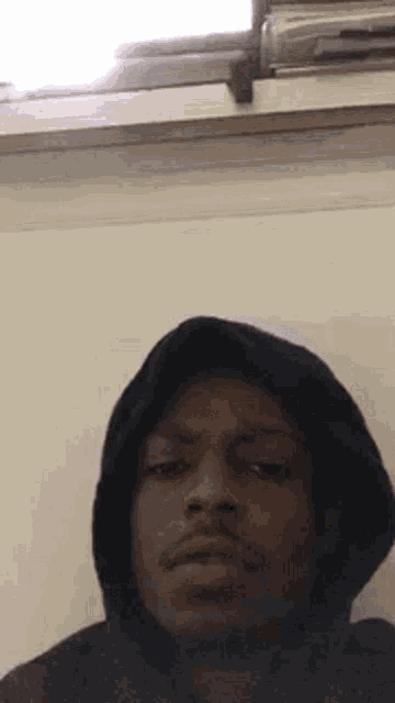 a man wearing a hooded jacket is making a funny face .