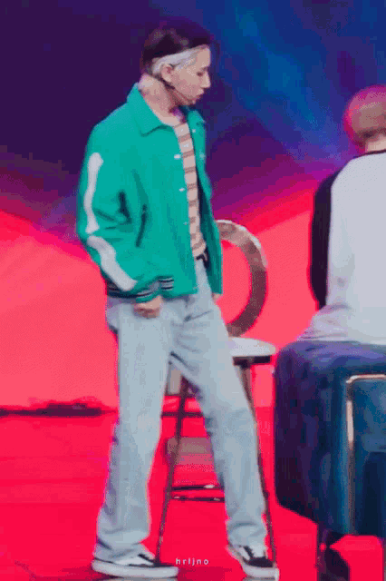 a man in a green jacket is standing on a chair